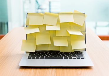 Laptop covered with yellow post-its.